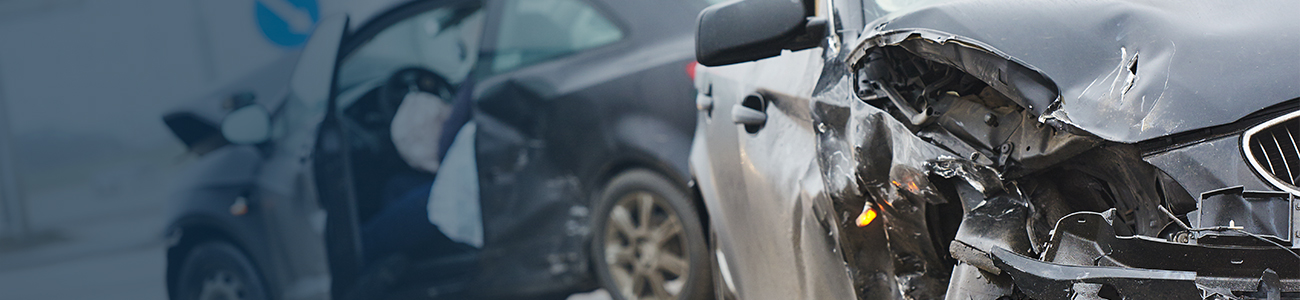 Crashed black car with significant frontal damage and debris scattered around, highlighting the aftermath of a severe vehicle accident.