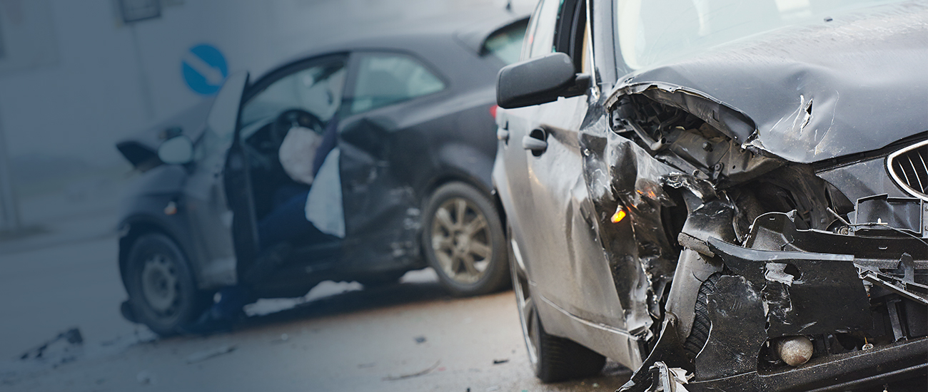 Crashed black car with significant frontal damage and debris scattered around, highlighting the aftermath of a severe vehicle accident.